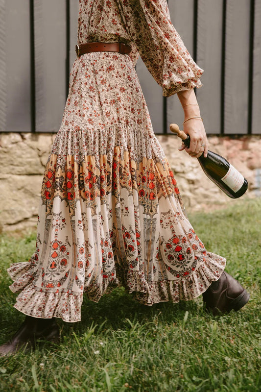 Woman in dress walking outside with champagne bottle